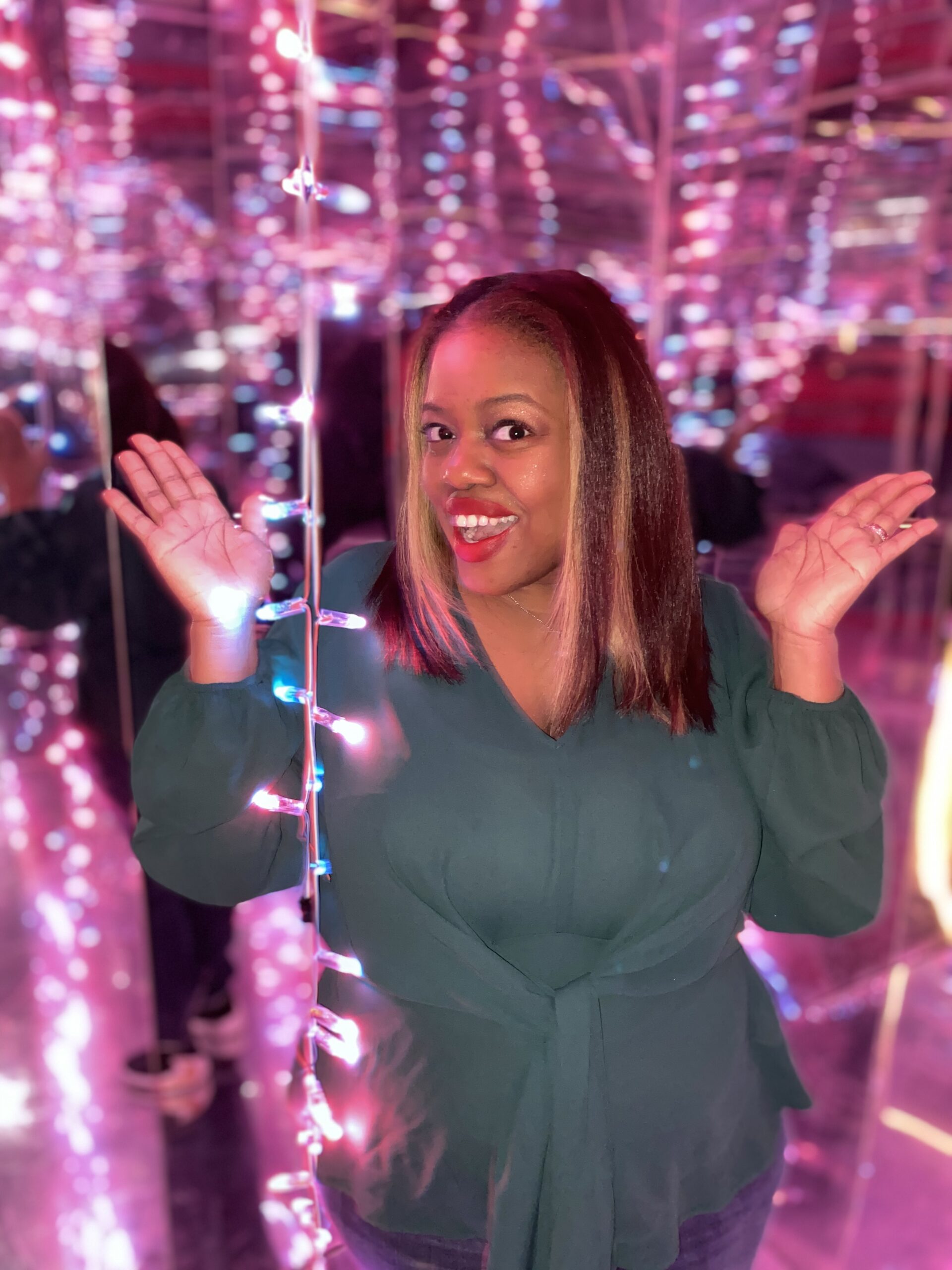 Danielle Williams smiling in front of a purple background with lights.