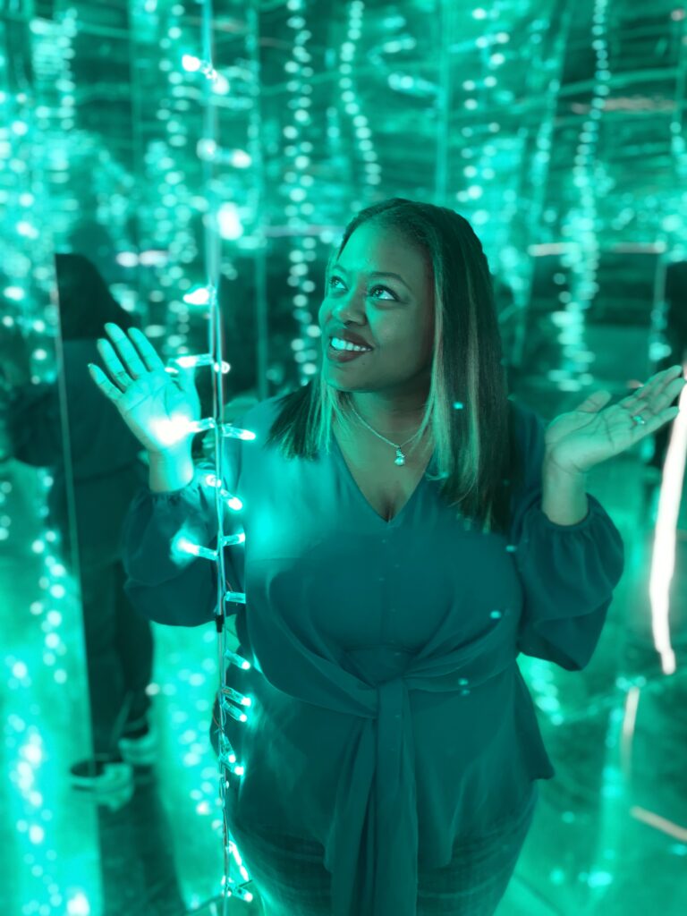 Danielle pictured in a green shirt with a green background and lighting.